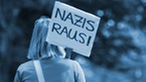 Eine Frau trägt ein Schild mit "Nazis raus!"