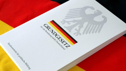 Das Grundgesetz liegt auf einer Deutschlandfahne