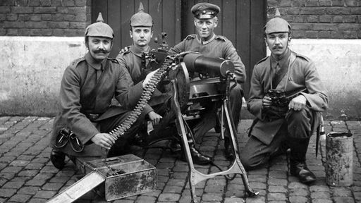Vier Soldaten posieren mit einem Maschinengewehr 