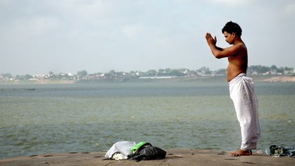 Ein Mann steht am Ganges und betet