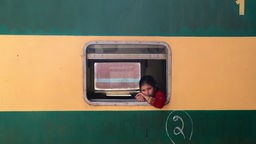 Ein Mädchen schaut aus einem Zugfenster auf den Bahnhof Peschawar.