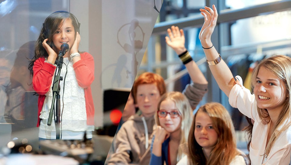 Mädchen mit Kopfhörern am Mikrofon. Jugendliche heben die Hände. 